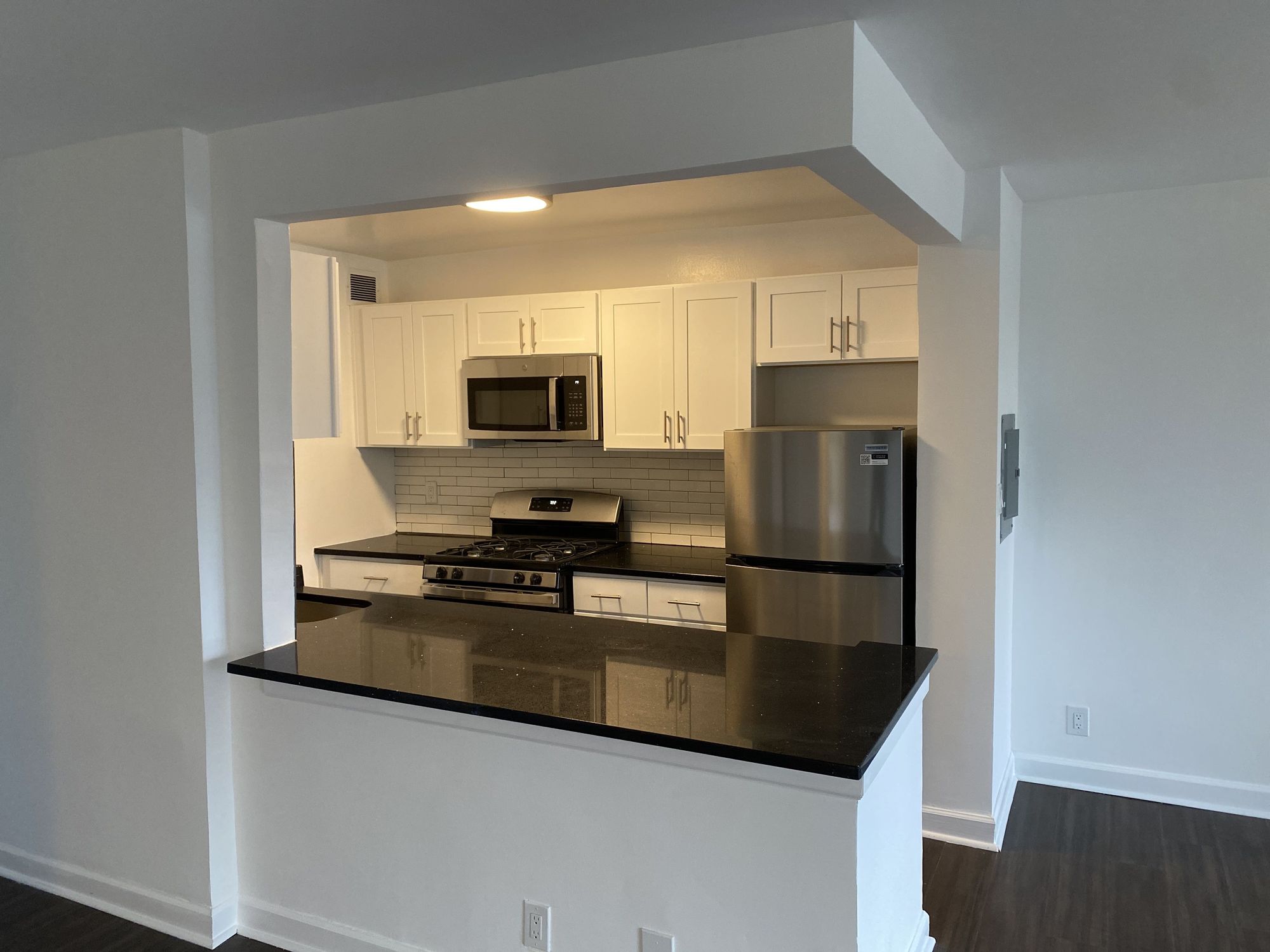 Sherwood Apartments renovated kitchen with white shaker cabinets and granite peninsula